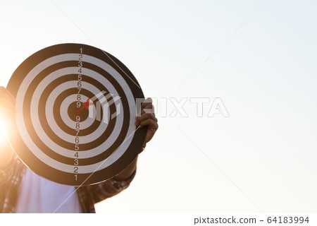 Man hand holding a target with darts hitting the 64183994