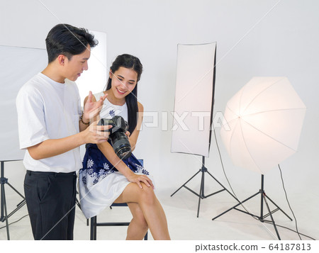 Asian photographers allow models to view pictures taken on the camera screen. 64187813