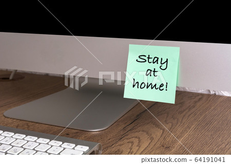 Computer with a sticker with the text Stay at home. Concept about quarantine and remote work. Computer with a sticker with the text Stay at home. Concept about quarantine and remote work. 64191041