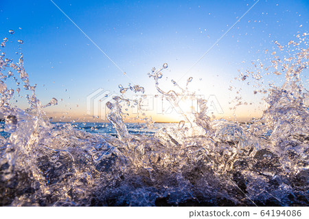 在日落的背景下濺起的海浪 64194086