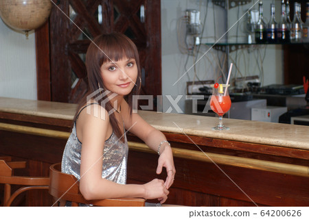 Young beautiful girl with cocktail at the counter in the cafe Young beautiful girl with cocktail at the counter in the cafe 64200626