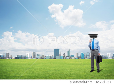 Camera headed man standing on green grass against modern cityscape Camera headed man standing on green grass against modern cityscape 64201085
