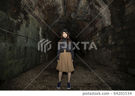 戴著帽子的年輕女子站在一條遠足路線的隧道中在兵庫縣竹島線的廢墟上 64201534
