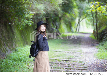 一位戴著帽子的年輕女士漫步在兵庫縣Takedao廢線的徒步旅行路線 一位戴著帽子的年輕女士漫步在兵庫縣Takedao廢線的徒步旅行路線 64201539