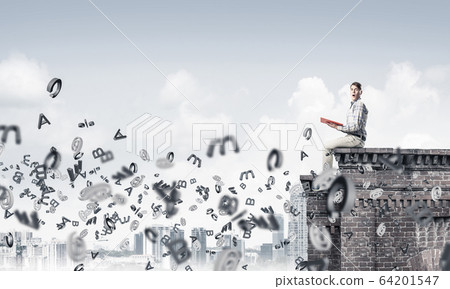 Man on roof edge reading book and symbols flying around Man on roof edge reading book and symbols flying around 64201547