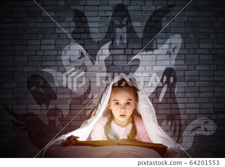 Scared little girl reading book in bed Scared little girl reading book in bed 64201553