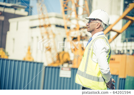 Senior foreman in glasses doing his job at building area on sunn 64201594
