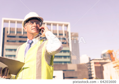 Man architector outdoor at construction area having mobile conve Man architector outdoor at construction area having mobile conve 64201600