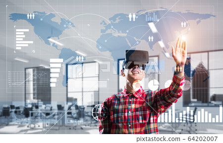 Young man in modern office interior experiencing virtual reality technology Young man in modern office interior experiencing virtual reality technology 64202007