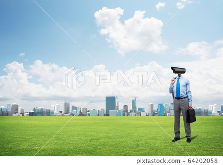 Camera headed man standing on green grass against modern cityscape Camera headed man standing on green grass against modern cityscape 64202058