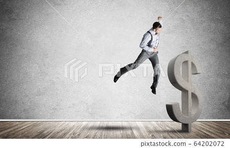 Determined banker man in empty concrete room breaking dollar figure Determined banker man in empty concrete room breaking dollar figure 64202072