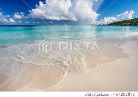 Ocean wave and cloudscape on tropical beach Grand Anse, La Digue Island, Seychelles Ocean wave and cloudscape on tropical beach Grand Anse, La Digue Island, Seychelles 64202078