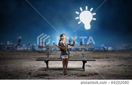 Young woman holding open book on bench 64202080