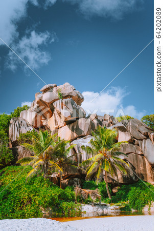 La Digue island, Seychelles. Grand Anse bizarrely formed shaped granite boulders with palm trees on sandy beach La Digue island, Seychelles. Grand Anse bizarrely formed shaped granite boulders with palm trees on sandy beach 64202089