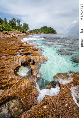 Old reef coastline and ocean waves on tropical Police Bay beach on Mahe Island, Seychelles Old reef coastline and ocean waves on tropical Police Bay beach on Mahe Island, Seychelles 64202131