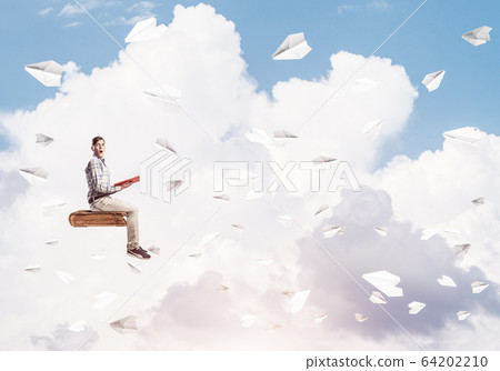 Handsome man student reading book and paper planes flying around 64202210