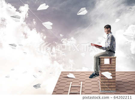 Handsome student guy reading book and paper planes flying in air 64202211