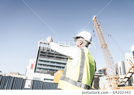 Senior foreman in glasses doing his job at building area on sunn Senior foreman in glasses doing his job at building area on sunn 64202343