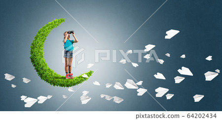 Concept of careless happy childhood with girl on green moon Concept of careless happy childhood with girl on green moon 64202434