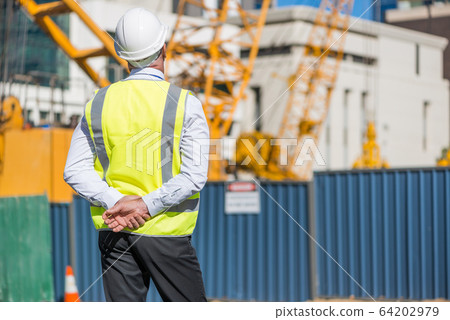 Senior foreman in glasses doing his job at building area on sunny day Senior foreman in glasses doing his job at building area on sunny day 64202979