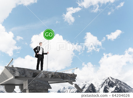 Young businessman holding street safety sign. 64204026