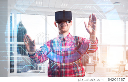 Young man in modern office interior experiencing virtual reality technology Young man in modern office interior experiencing virtual reality technology 64204267
