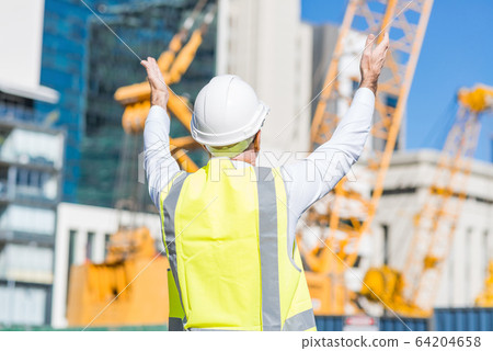 Senior foreman in glasses doing his job at building area on sunny day Senior foreman in glasses doing his job at building area on sunny day 64204658