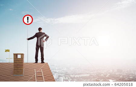 Businessman on house top showing sign with exclamation mark. Mixed media 64205018