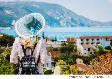 Tourist female with blue sun hat enjoying greek cute and vivid colored Assos town on Kefalonia island, Greece 64206994