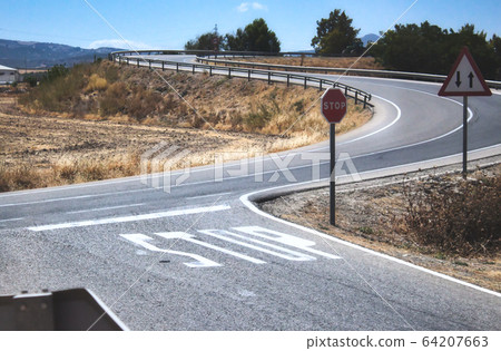 Stop sign and markings on the road at a two-way 64207663