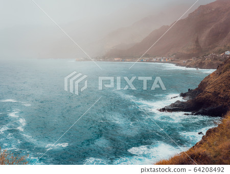 Paul Pombas, Santo Antao Cape Verde. Bluff volcanic coastline covered by sunlight penetrates dust. Silhouette of mountain ridges and ocean waves Paul Pombas, Santo Antao Cape Verde. Bluff volcanic coastline covered by sunlight penetrates dust. Silhouette of mountain ridges and ocean waves 64208492