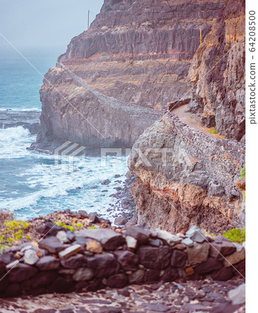 Santo Antao. Cape Verde. Stunning scenery of the coastal trail. Steep black cliffs stretched out ahead, huge waves crashing against steep rocky shore Santo Antao. Cape Verde. Stunning scenery of the coastal trail. Steep black cliffs stretched out ahead, huge waves crashing against steep rocky shore 64208500