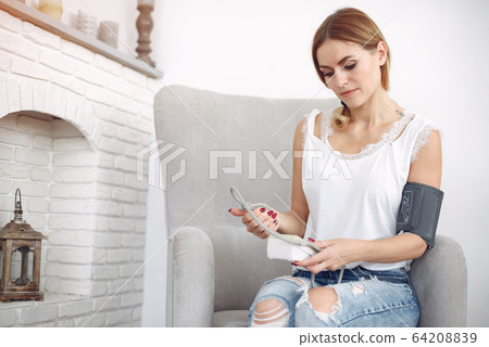 Woman measures herself pressure at home 64208839