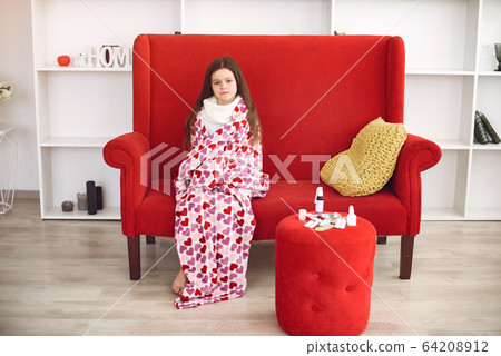 Little girl sitting at home with a cold 64208912