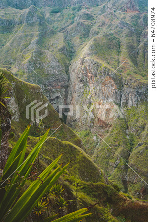 Santo Antao, Cape Verde. Breathtaking view of canyon with steep cliff and winding riverbed with lush green vegetation Santo Antao, Cape Verde. Breathtaking view of canyon with steep cliff and winding riverbed with lush green vegetation 64208974