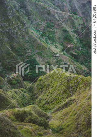 Vertiginous mountains ridge with some houses, valleys and peaks covered with yellow grass and green mango trees Vertiginous mountains ridge with some houses, valleys and peaks covered with yellow grass and green mango trees 64208995