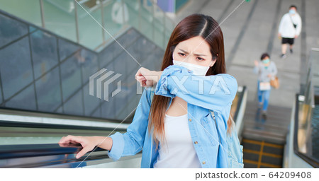 woman coughs in her elbow woman coughs in her elbow 64209408