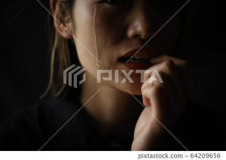 Woman biting nails while shedding tears Woman biting nails while shedding tears 64209656