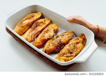 Female hand holding a tray with torrijas, a typical Spanish sweet fried toasts of sliced bread soaked in eggs and milk. Female hand holding a tray with torrijas, a typical Spanish sweet fried toasts of sliced bread soaked in eggs and milk. 64209804