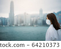 Young asian woman wearing protective face mask in city due to the polluted air or pm 2.5 and Coronavirus disease or COVID-19 outbreak situation in Hong Kong China and all of landmass in the world. 64210373