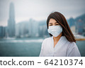 Young asian woman wearing protective face mask in city due to the polluted air or pm 2.5 and Coronavirus disease or COVID-19 outbreak situation in Hong Kong China and all of landmass in the world. 64210374