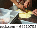 The chef rolling out the dough with his hands 64210758