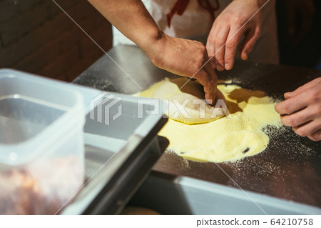 The chef rolling out the dough with his hands The chef rolling out the dough with his hands 64210758