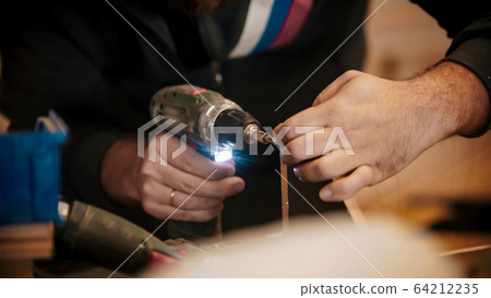 Carpentry industry - worker drilling the holes in plywood piece 64212235