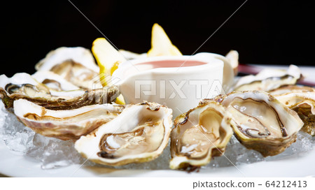 Opened fresh oysters with lemon on dish. Shallow dof 64212413