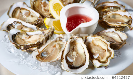 Opened fresh oysters with lemon on dish. Shallow dof Opened fresh oysters with lemon on dish. Shallow dof 64212437