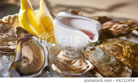 Opened fresh oysters with lemon on dish. Shallow dof 64212454