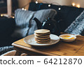 Pancakes with honey on wooden tray in cozy room. 64212870