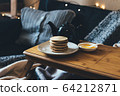 Pancakes with honey on wooden tray in cozy room. 64212871