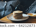 Pancakes with honey on wooden tray in cozy room. 64212873